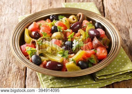 Tomato And Green Pepper Salad With Anchovies And Olives Close-up In A Bowl. Horizontal