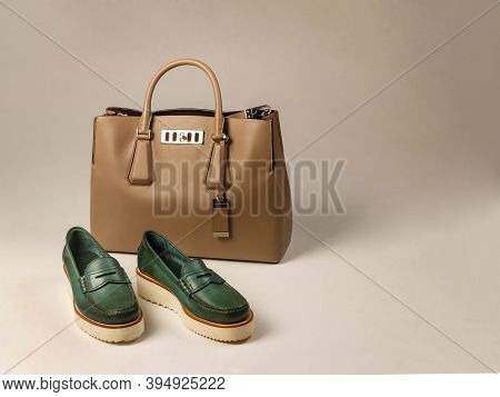 A Pair Of Green Women's Shoes With Thick Soles. Nearby Is A Light-colored Women's Leather Bag. Side 