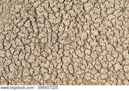 Part Of A Huge Area Dried Land Suffering From Drought-in Cracks. Dry Water Reservoir. Dry Clay Soil 