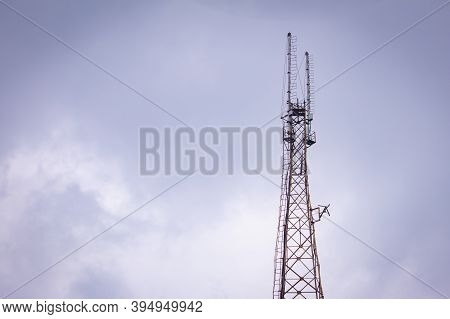 Communication Tower With The Overcast Sky Background.