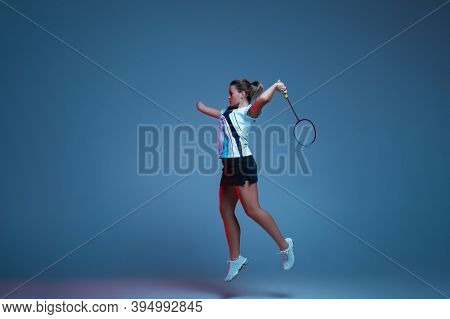 In Jump. Beautiful Handicap Woman Practicing In Badminton Isolated On Blue Background In Neon Light.