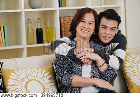 Happy Teenage Vietnamese Young Man Hugging His Mother From Behind And Looking At Camera When Thay Ar