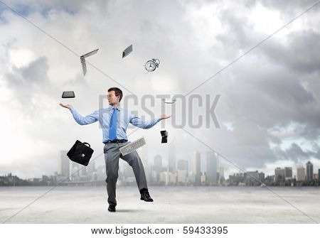 Young businessman juggling with business items against urban scene