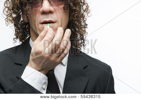 Cropped shot mediterranean man in a suit taking colourful pill