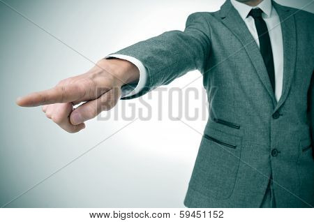 a man wearing a suit pointing with the finger the way out