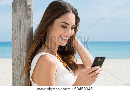 Portrait Of A Beautiful Young Woman At Beach Looking At Cellphone