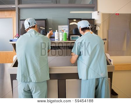Rear view of multiethnic surgeons washing hands at washbasin before surgery