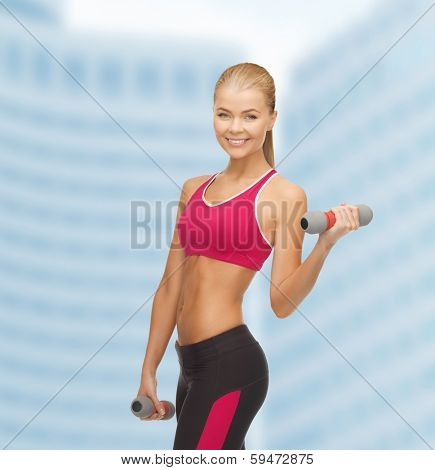 fitness and dite concept - young sporty woman with light dumbbells