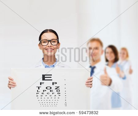 healthcare, advertisement and medicine concept - smiling female doctor in eyeglasses with eye chart