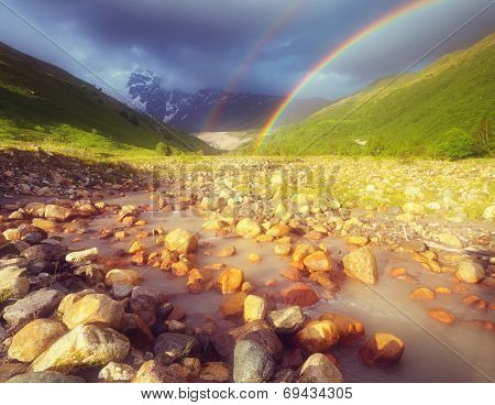 Summer landscape with a rainbow in the mountains above the river. Zemo Svaneti, Georgia. Soft effect. Color toning