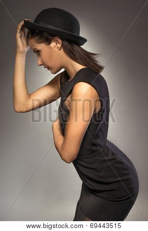 elegant woman weating hat and black dress on grey