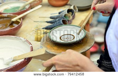 BRASOV, ROMANIA - AUGUST 27, 2014: Woman painting traditional plates at a fair with specific design
