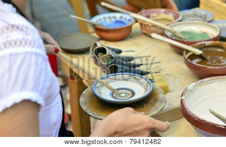 BRASOV, ROMANIA - AUGUST 27, 2014: Woman painting traditional plates at a fair with specific design