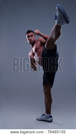 Portrait of a muscular man practicing body combat over gray background
