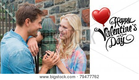 Hip young couple standing by railings against cute valentines message