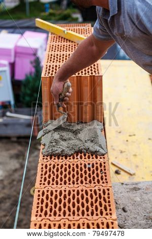 anonymous construction worker on a construction site in home building erected a wall of bricks. solid brick wall of a house. icon image for undeclared work and botch