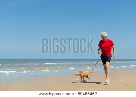 Senior runner with dog at the beach