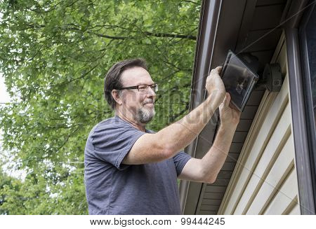 Electrician Changing Light Bulb In Exterior Light