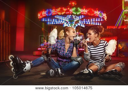 Girls wearing roller skates and eating candyfloss