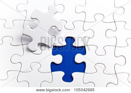 Plain white jigsaw puzzle on Blue background autism awerness symbol