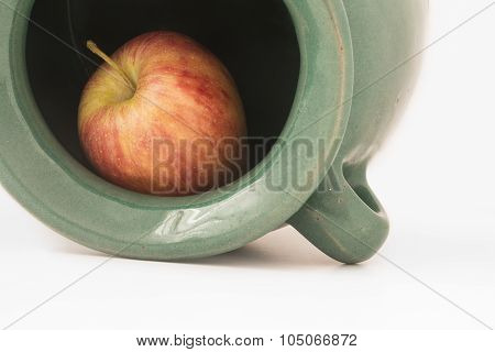 Close Up View Of A Red Apple Inside The Greenish Earthen Jar