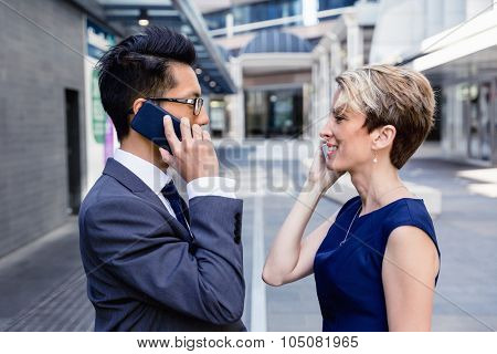 Business people standing in stret with their mobiles