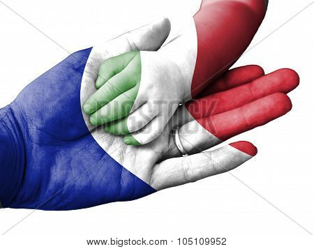 Adult Man Holding A Baby Hand With France And Italy Flags Overlaid. Isolated On White