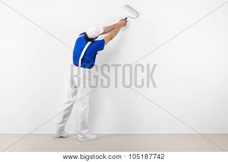 Painter With Paintroller On White Wall