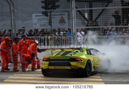 KUALA LUMPUR, MALAYSIA - AUGUST 09, 2015: Safety marshals put out the fire in the Lamborghini car driven by Byron Tong after it crashed in the race at the 2015 Kuala Lumpur City Grand Prix.