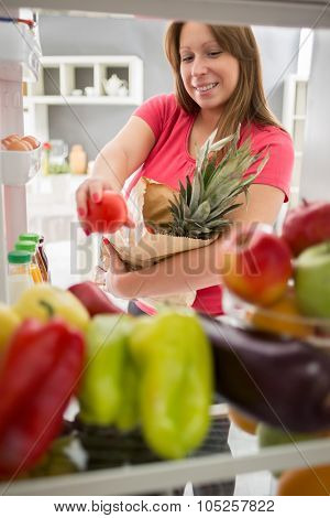 Young woman from purchase  full fridge with fruit and vegetables