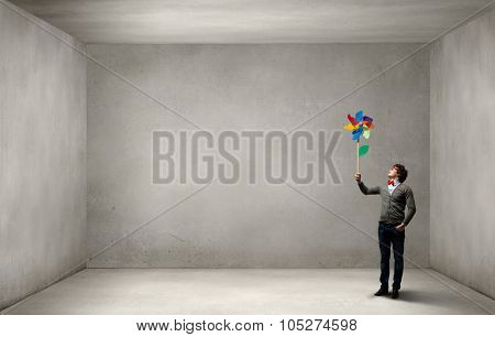 Young happy guy in casual with colorful windmill in hand