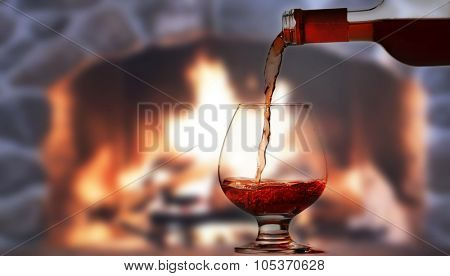 Pouring rred wine in front of fireplace
