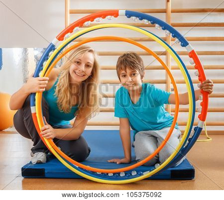 Happy, sports family, mother and son looking through hula hoops