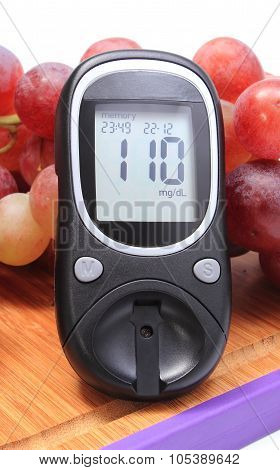 Glucose Meter And Fresh Natural Grapes On Cutting Board