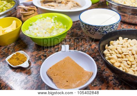 Bowls of different ingredients spread out on granite surface including green peas, onions, abbas, co
