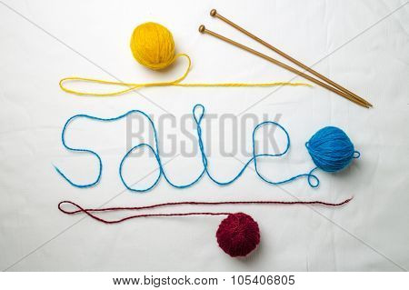 Word sale written multicolored yarn threads coiled into balls on a white background