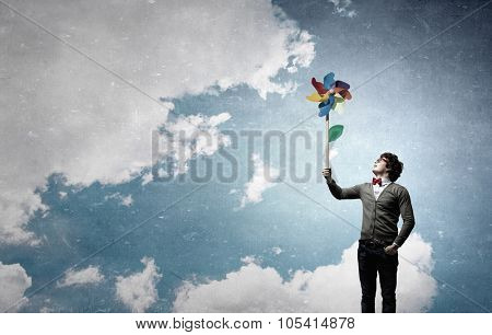Young happy guy in casual with colorful windmill in hand