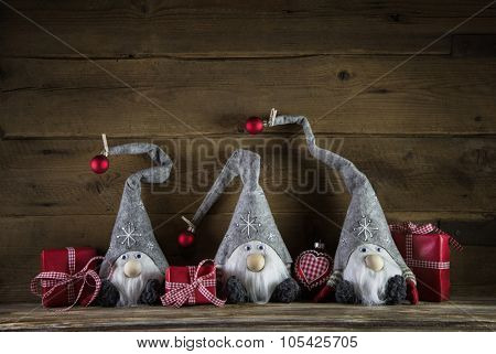 Three santa with red white checked christmas gift boxes on wooden old background.