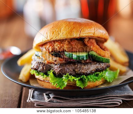 burger with onion rings and barbecue sauce with pepperjack cheese on plate