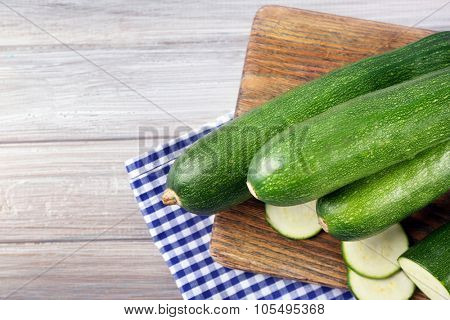 Fresh sliced zucchini on cutting board, on wooden background