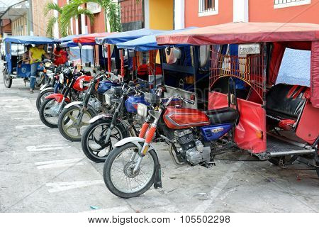 IQUITOS, PERU - OCTOBER 17, 2015: MotoKars parked in a line. The motorcycle with passenger cab attached is a common form of transportation in the remote Amazon city.