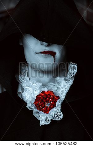 Handsome vampire man wearing elegant tailcoat stands in the old medieval castle. Halloween.