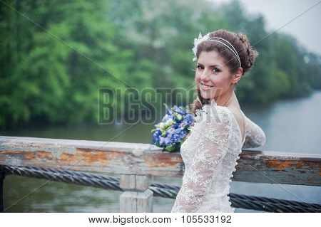 Portrait of a beautiful bride in white wedding dress smiling under rain