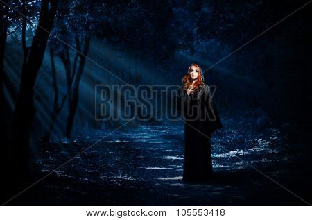 Young witch in night forest