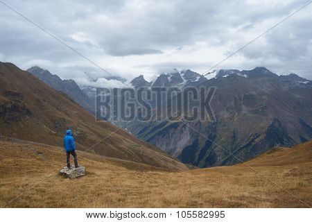 Tourists in the mountains standing on a rock and looking over the valley. Overcast. Main Caucasian ridge. Zemo Svaneti, Georgia 