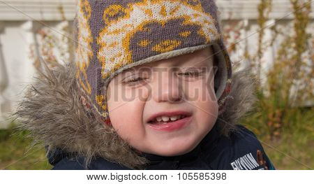 Face Of The Little Boy In A Warm Cap With The Covered Eyes And A Contemptuous Grimace