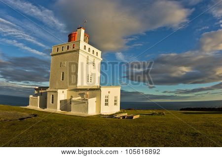 Lighthouse at Dyrholaey rock at sunset with dramatic sky