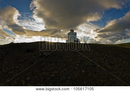Lighthouse at Dyrholaey rock at sunset with dramatic sky