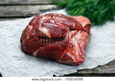 Raw Beef Ox Cheek on crumpled paper, decorated with Dill. on old