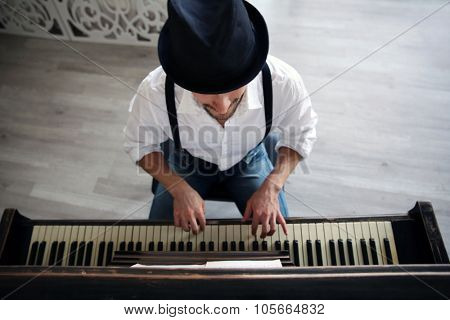Handsome young man in hat making piano music, topside view